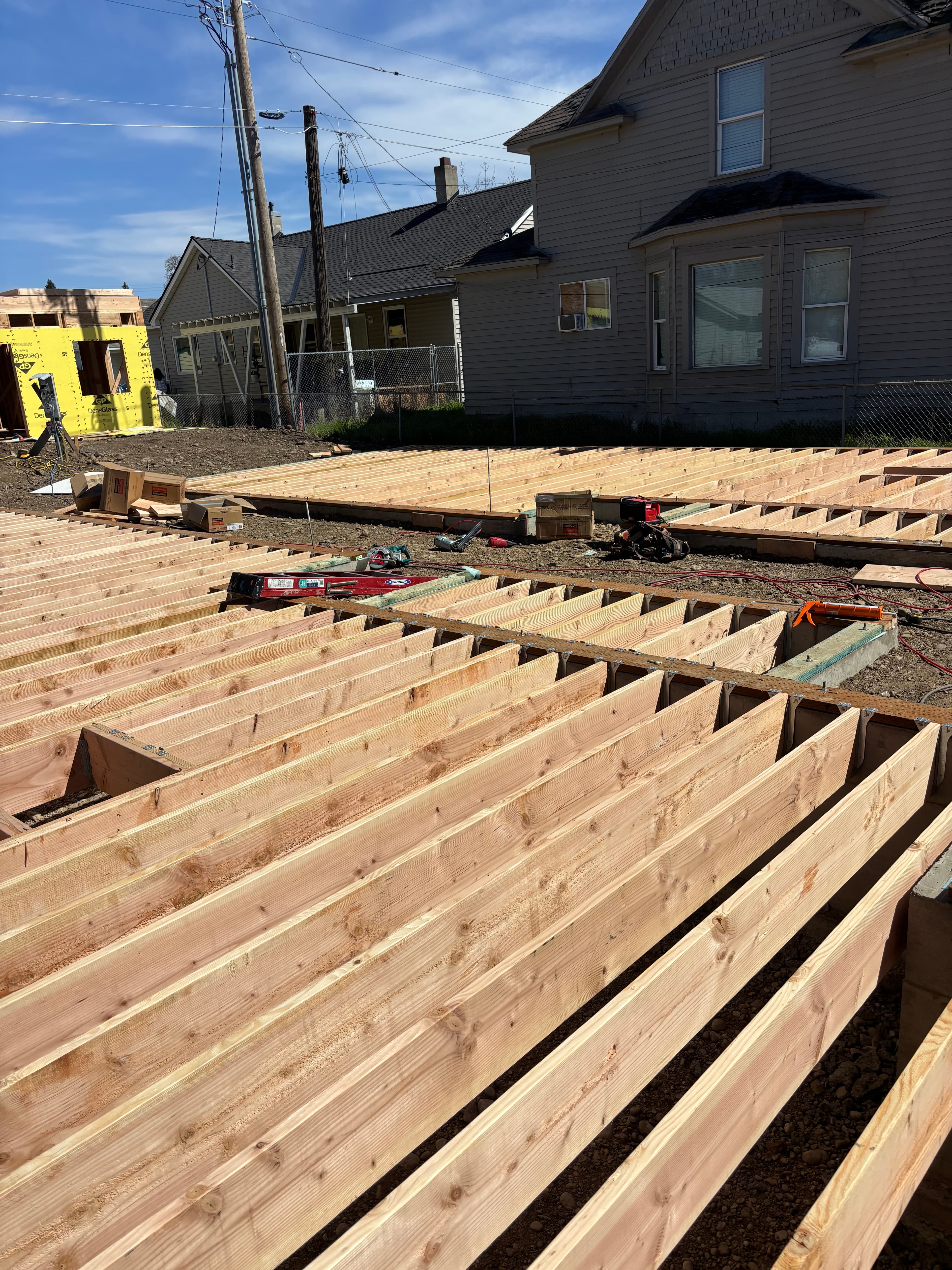 Rows of parallel wooden joists for a deck under construction next to a house.