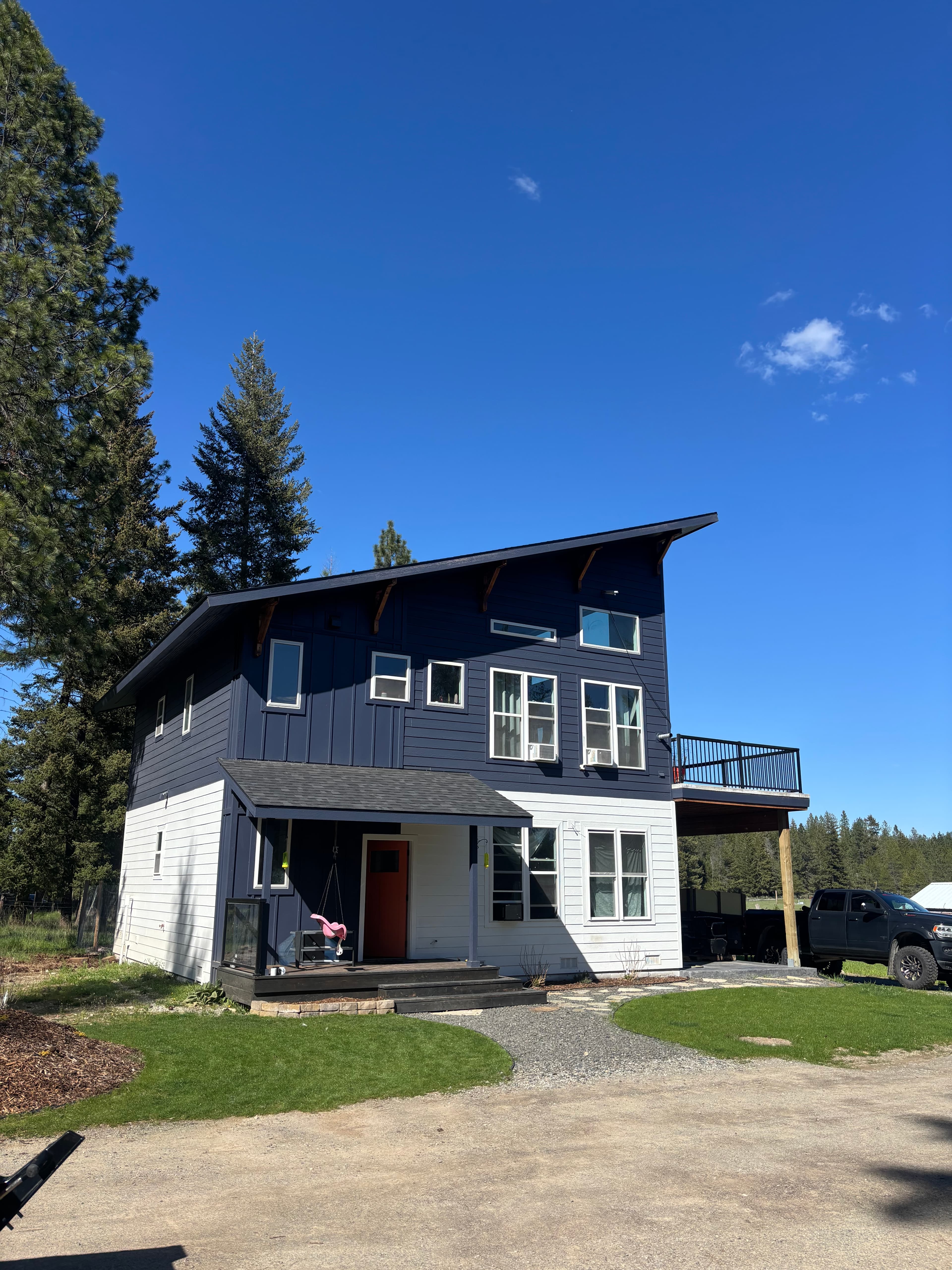 Modern navy and white two-story house with many windows under a clear blue sky.